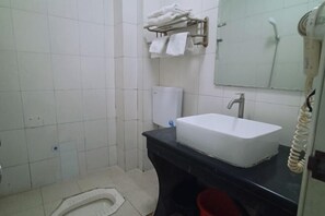 A bathroom with a white sink, a black countertop, a towel rack with towels, a toilet, and a hand dryer. - Fogang Xingshu Fashion Hotel (Fogang)