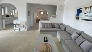 Ein modernes Wohnzimmer mit grauem Sofa, einem Couchtisch und einem Essbereich mit Tisch und Stühlen.