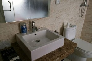 A bathroom with a white sink, a toilet, and a marble wall. - Jiangnan Business Hotel (Dongning)