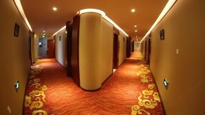 A hotel corridor with a red carpet and cream-colored walls.