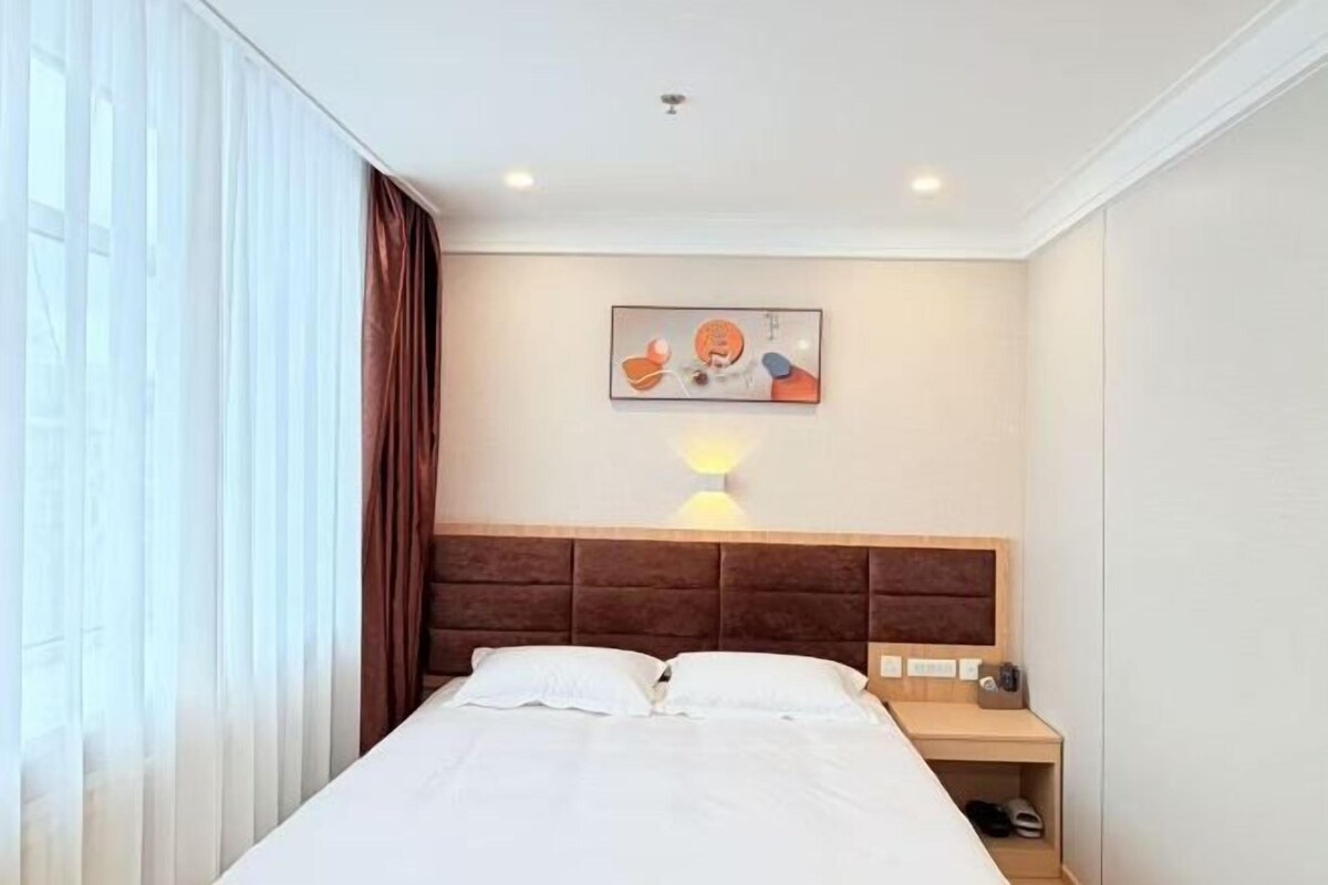 Una habitación de hotel con una cama, una mesita de noche, una lámpara y un cuadro en la pared.
