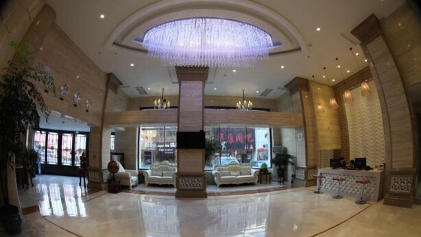 A spacious lobby with a large chandelier, seating area, and a reception desk.