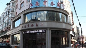A hotel with a curved facade, large windows, and a sign indicating a price of 168 yuan for a room.