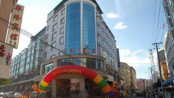 A multi-story hotel with a curved facade, a large entrance arch, and a visible sign indicating amenities.