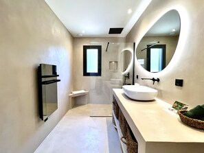Een moderne badkamer met een grote spiegel, een wastafel en een handdoekhouder.