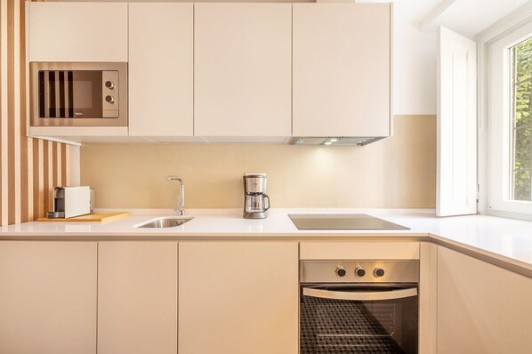 A modern kitchen with a built-in microwave, a coffee maker, a sink, and a dishwasher.