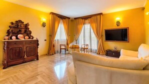 Ein Wohnzimmer mit Sofa, einer Holzkabine mit Dekoration, einem Fernseher und einem Essbereich mit Stühlen und Tisch.
