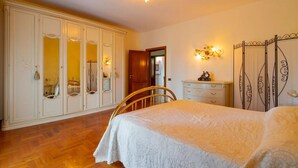 Ein Schlafzimmer mit Bett, Kleiderschrank, Stuhl und Spiegel.