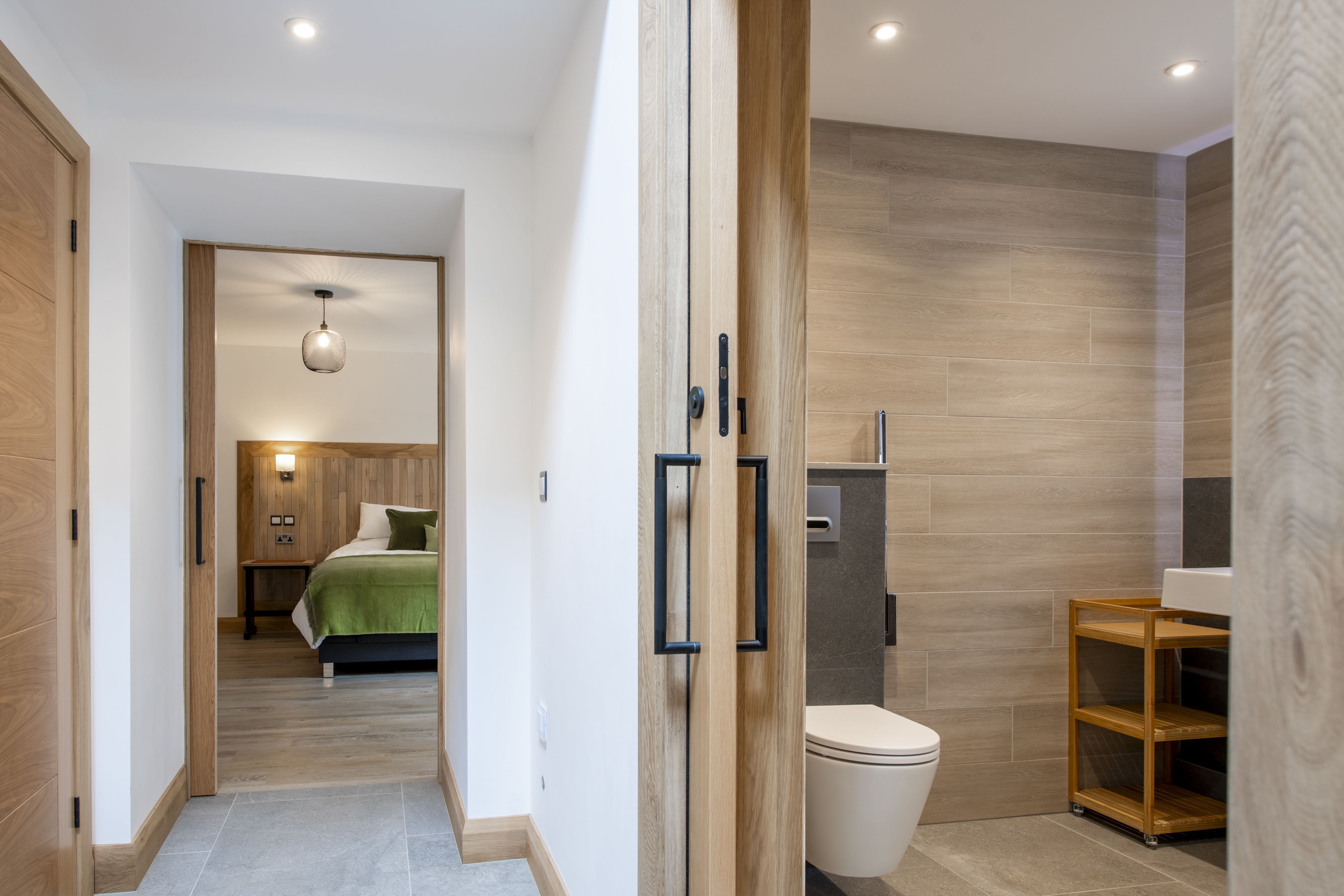 A modern bathroom with a toilet, sink, and wooden shelving.