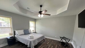 Un dormitorio con cama, ventilador de techo y ventana con persianas.