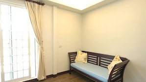 Una habitación con un banco de madera, una ventana con cortinas y un suelo de baldosas.