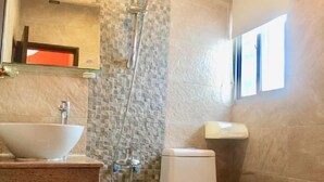Un baño con lavamanos blanco, ducha e inodoro.
