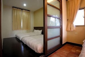 A room with a bed, a window with curtains, and a wooden sliding door. - Li Ting Hostel (Pingtung)