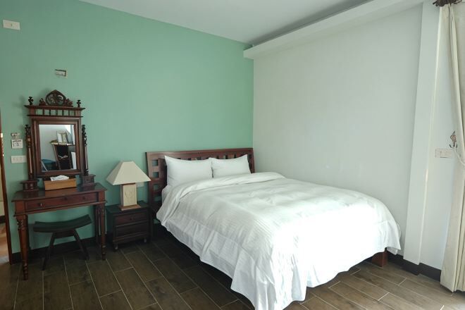A bedroom with a bed, a nightstand, a mirror, and a desk.