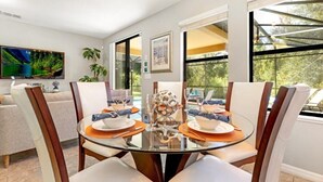 A dining area with a glass table, white chairs, and a decorative centerpiece. - Luxury 4BR Retreat w/ Pool, Game Room & Close to Disney Attractions (Davenport)