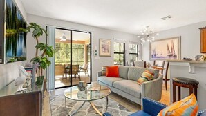 A modern living room with a sofa, coffee table, and a dining area with chairs. - Luxury 4BR Retreat w/ Pool, Game Room & Close to Disney Attractions (Davenport)