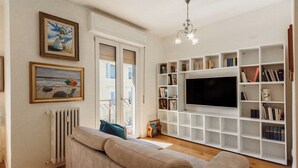 Una sala de estar con un sofá, un televisor y una estantería.