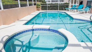Una piscina con dos jacuzzis, rodeada de sillones de descanso y vistas a un edificio.