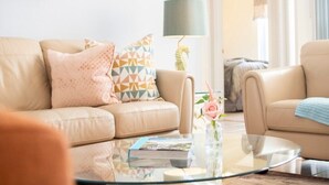 Una sala de estar con un sofá beige, una mesa de centro de vidrio y una lámpara.