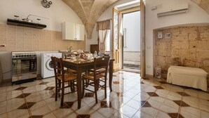 A kitchen with a dining table, chairs, a stove, a washing machine, and a laundry basket.