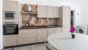 Una cocina compacta con electrodomésticos integrados, microondas, horno y fogones.