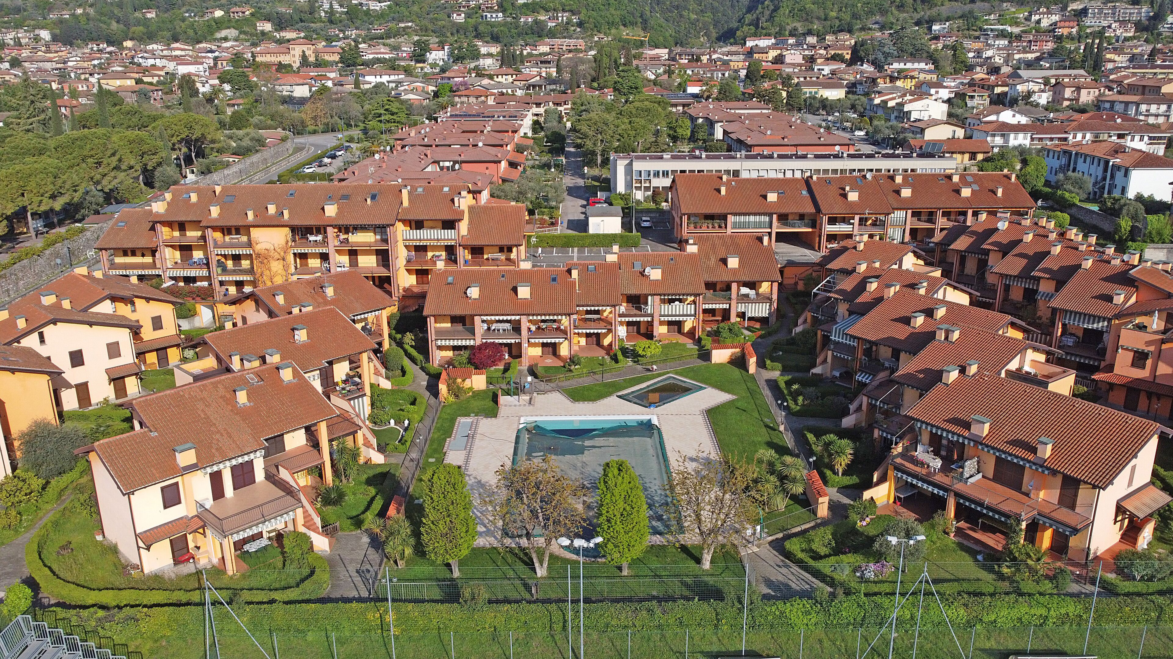 Zona residencial con varios edificios de apartamentos, un patio central con piscina y abundante vegetación.
