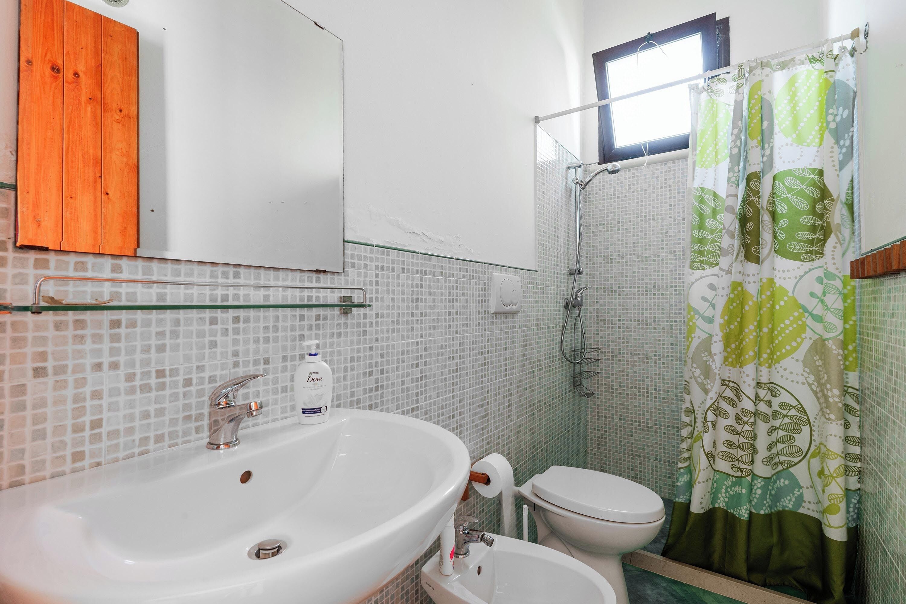 Une salle de bain avec un lavabo blanc, des toilettes et un rideau de douche.