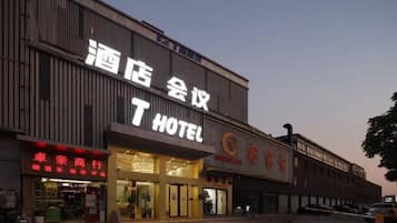 A hotel with a prominent sign, a storefront with signage, and a parking area.