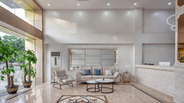 A spacious lobby with a high ceiling, a chandelier, a seating area with a sofa and chairs, a reception desk, and a large window. - Guangzhou T Hotel (ChangPan Subway Station) (Guangzhou)