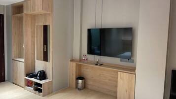 Una habitación moderna con un mueble de entretenimiento de madera, un televisor montado y un cubo de basura.