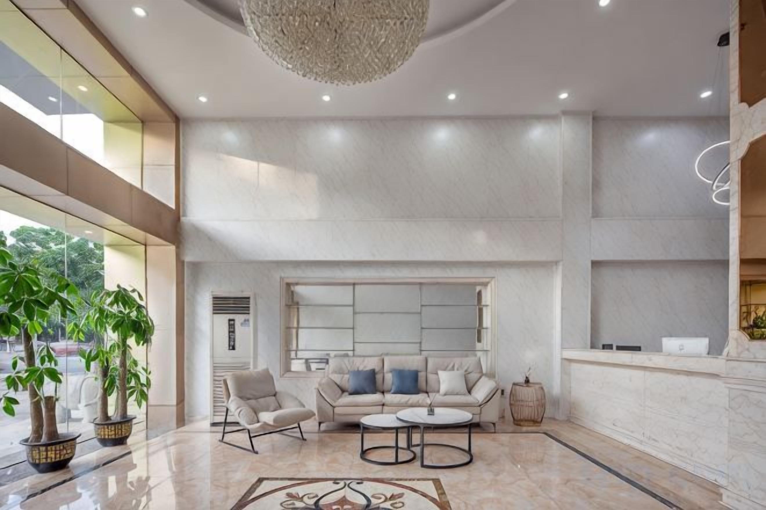 A spacious lobby with a seating area, a chandelier, and a large window.