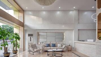 A spacious lobby with a seating area, a chandelier, and a large window.