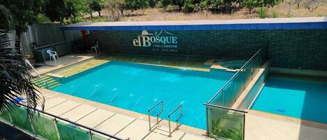 Una piscina con borde de azulejos y un cartel que dice "el Bosque".