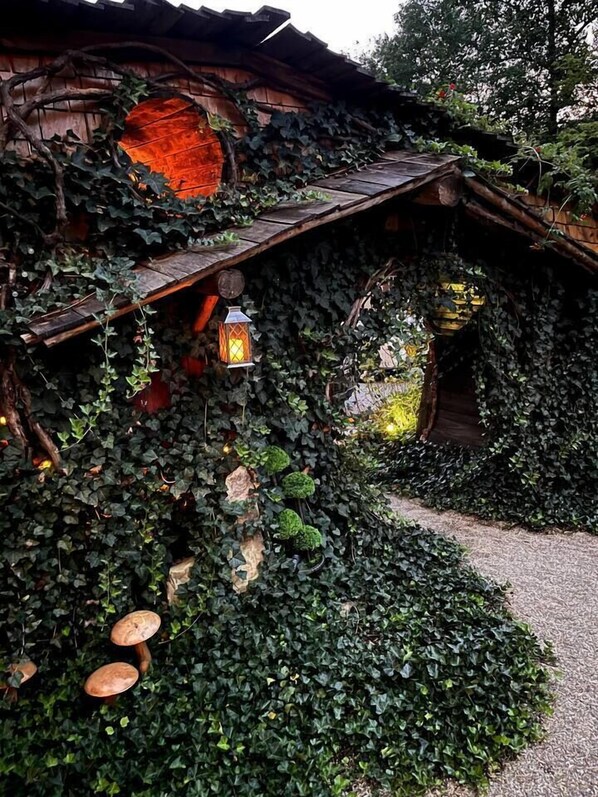 A rustic building with a wooden roof, ivy-covered walls, and a lantern.