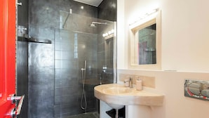 A modern bathroom with a glass-enclosed shower, a sink with a marble countertop, and a mirror above it.