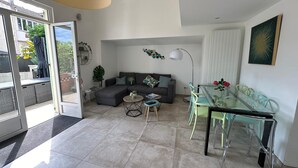 A modern living room with a sofa, coffee table, and dining area with chairs. - Pretty harbour house with garden (Mandelieu-la-Napoule)