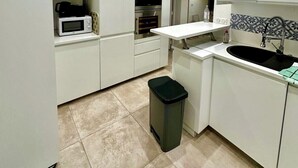 A modern kitchen with white cabinets, a built-in microwave, an oven, and a sink with a faucet. - Pretty harbour house with garden (Mandelieu-la-Napoule)