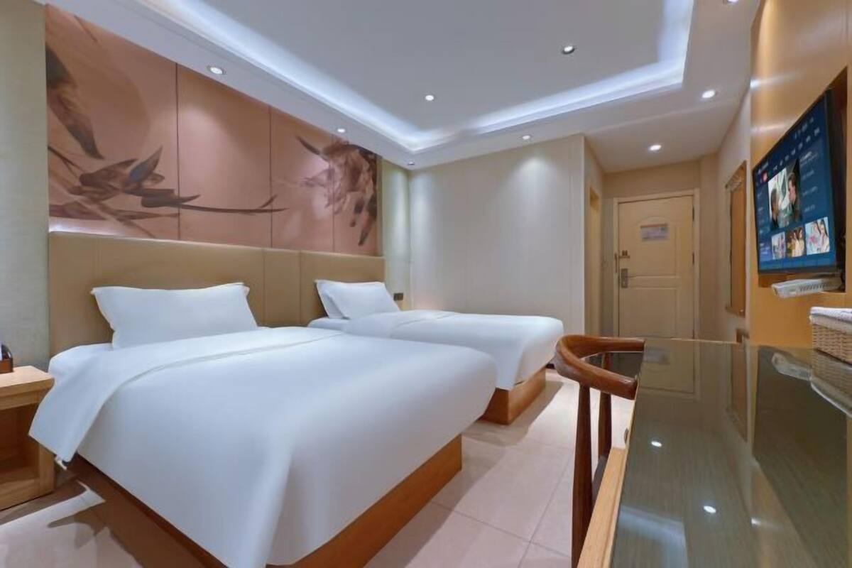 A hotel room with two beds, a television, and a wall mural.