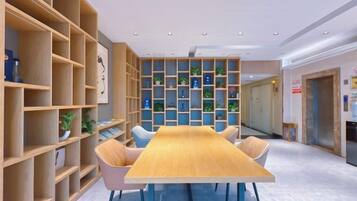 Un salón de conferencias con una larga mesa de madera, sillas y estanterías empotradas con plantas.
