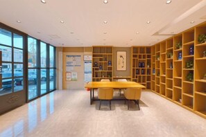 A spacious room with a large table and chairs, surrounded by bookshelves, and large windows providing a view of the outside. - Home Inn Alliance Huayi Hotel (Tancheng Railway Station Tanguo Ancient City) (Tancheng)