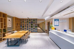 A reception area with a reception desk, seating area, and shelving units. - Home Inn Alliance Huayi Hotel (Tancheng Railway Station Tanguo Ancient City) (Tancheng)