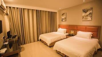 A hotel room with two beds, a desk with a computer, and a TV.