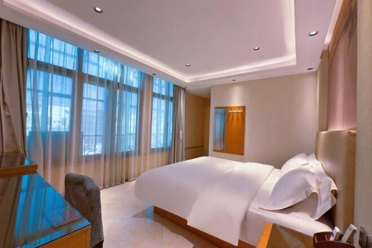 A modern hotel room with a large bed, a desk, and a chair.