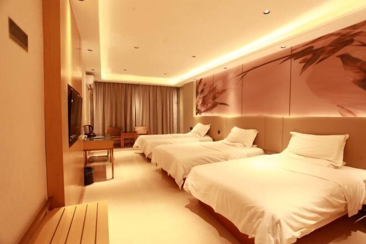 A hotel room with two beds, a desk, and a large wall mural.