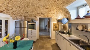 A kitchen with stone walls, a stainless steel refrigerator, an oven, and a sink.