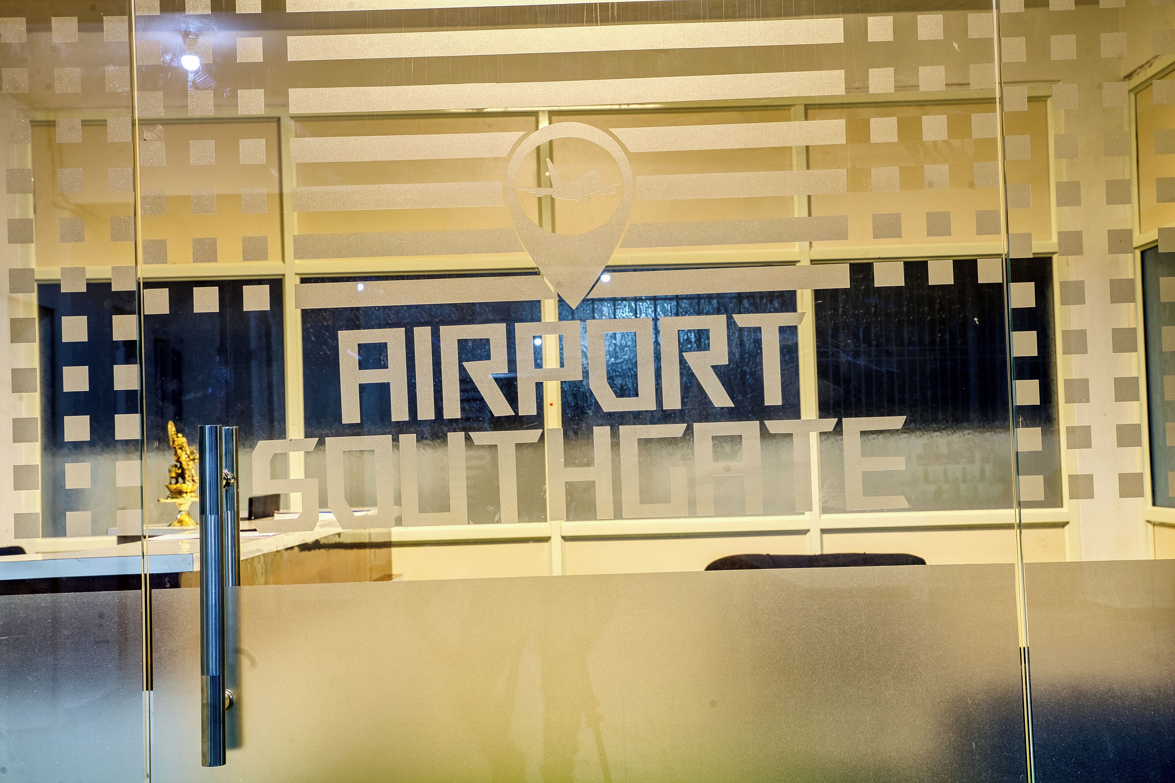 A glass partition with an airport sign and a location pin.