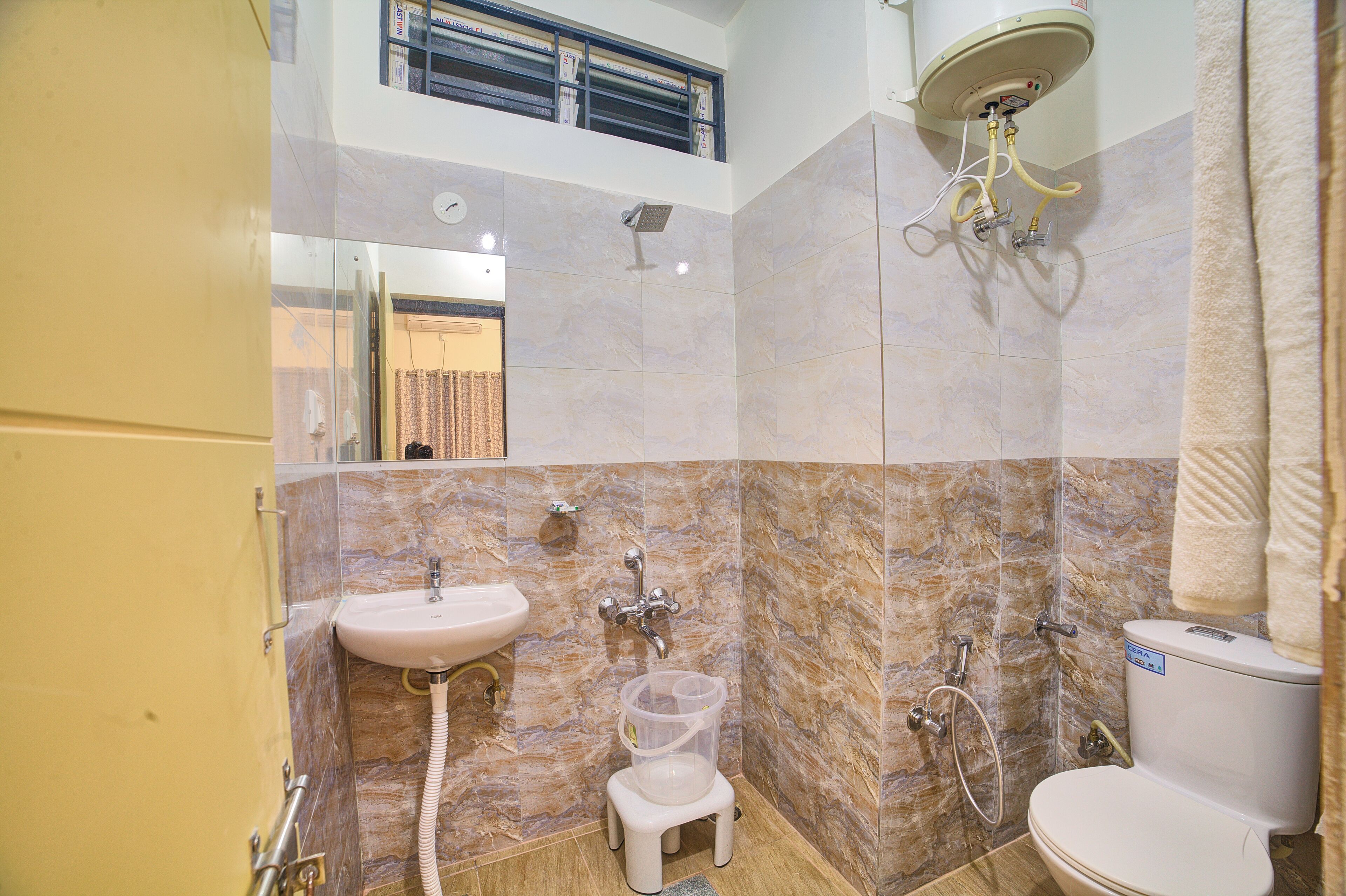 Un baño con lavamanos, inodoro, ducha y un taburete pequeño.