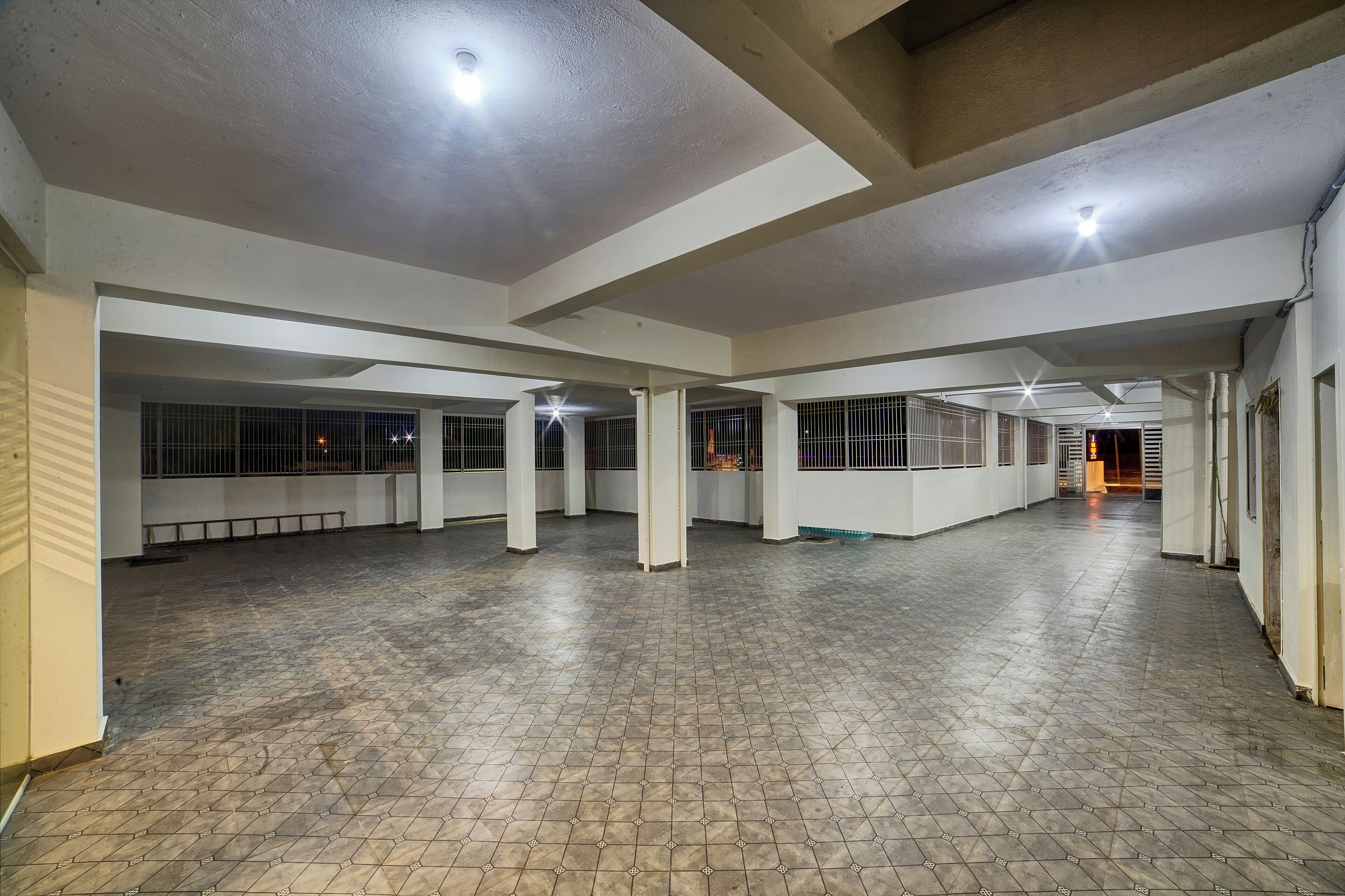 Un espacio interior amplio con suelo de baldosas, paredes blancas y varias columnas.