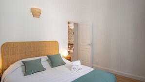 Une chambre à coucher comprenant un lit, des oreillers, une lampe de chevet et une porte donnant sur un coin repas.