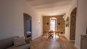 Un vaste espace de vie doté d’un plancher en bois, d’un canapé, d’une table à manger avec des chaises et d’un mur en pierre.